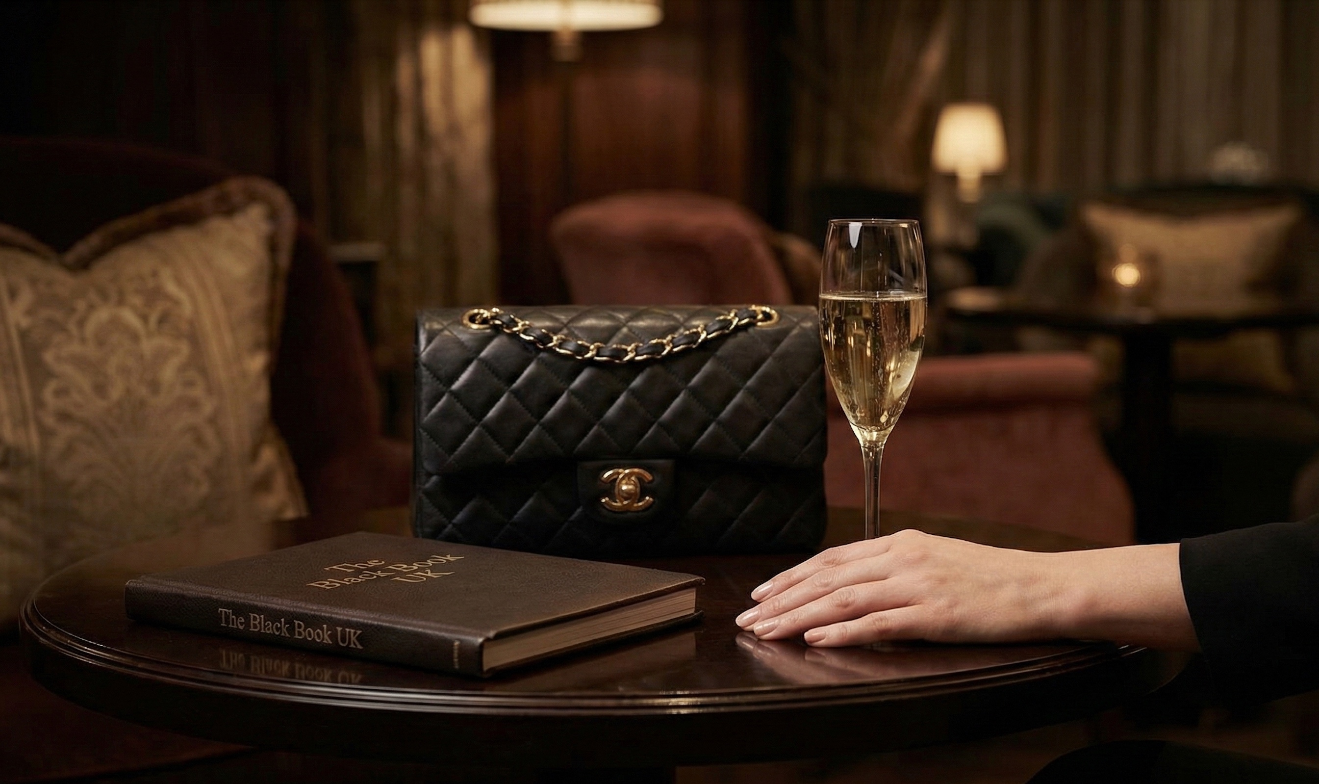 Exclusive Mayfair lounge setting with Chanel bag, champagne flute, and Black Book UK.